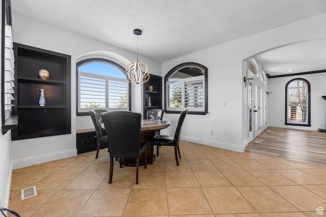 dining area featuring light tile patterned floors, visible vents, a textured ceiling, and french doors