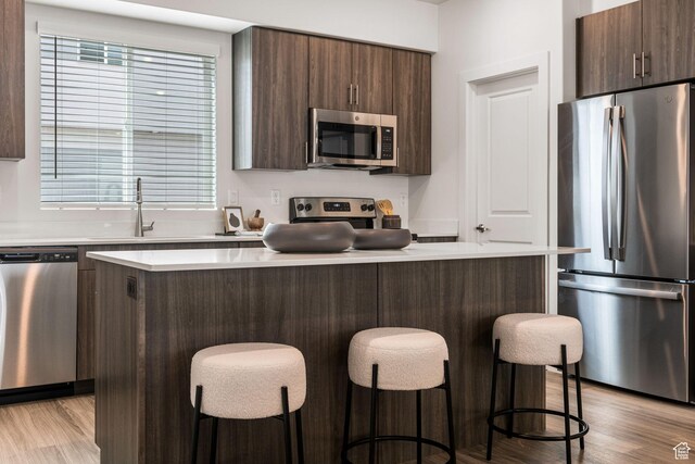 2321 W Leigh Ln Unit M55, West Haven, UT 84401 - kitchen featuring light wood-style floors, a center island, appliances with stainless steel finishes, and dark brown cabinetry