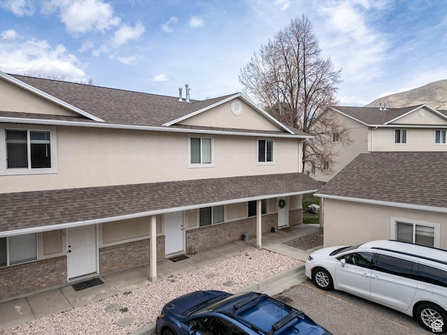 view of front facade featuring stucco siding, roof with shingles, and a porch