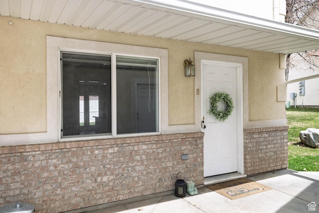 entrance to property featuring stucco siding and brick siding