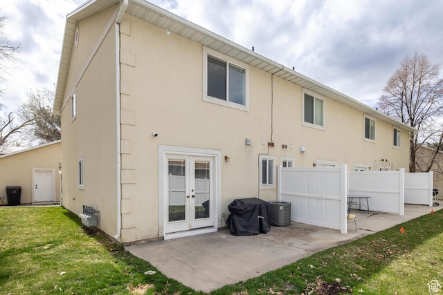 back of house featuring french doors, fence, a lawn, a patio, and stucco siding
