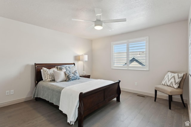 bedroom with visible vents, baseboards, wood finished floors, and a textured ceiling