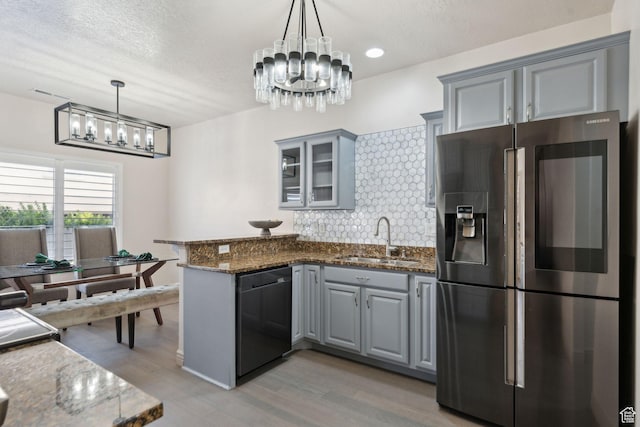 kitchen featuring stainless steel refrigerator with ice dispenser, a chandelier, black dishwasher, a sink, and gray cabinetry