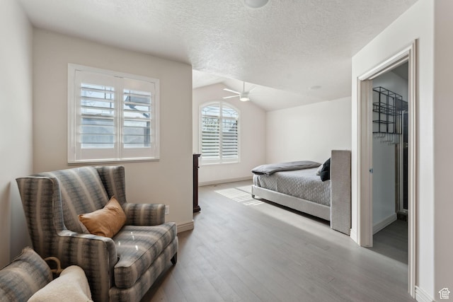 bedroom with ceiling fan, a textured ceiling, wood finished floors, lofted ceiling, and baseboards
