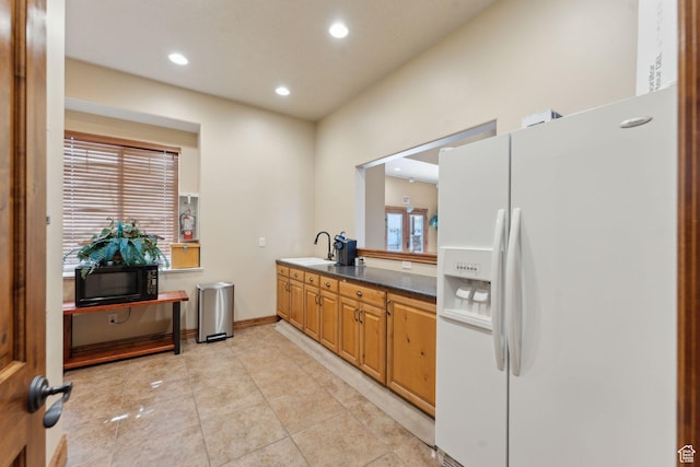 kitchen with white fridge with ice dispenser, black microwave, recessed lighting, dark countertops, and baseboards