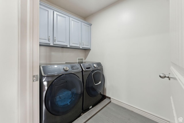 laundry area with independent washer and dryer, baseboards, and cabinet space