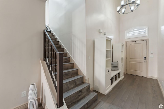 entrance foyer with an inviting chandelier, baseboards, dark wood-style floors, and stairway