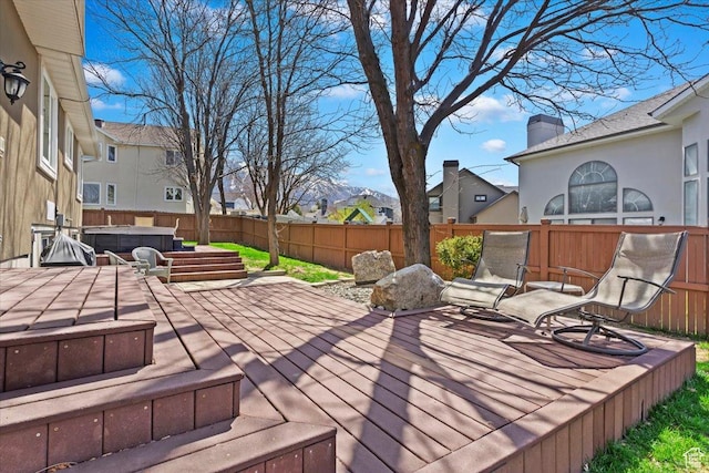 deck featuring a fenced backyard, a residential view, and a hot tub