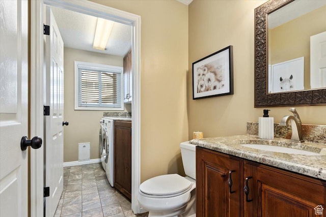 bathroom featuring washer and dryer, vanity, baseboards, and toilet