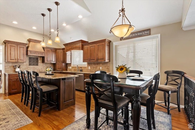 kitchen featuring custom range hood, wood finished floors, decorative backsplash, and a kitchen island