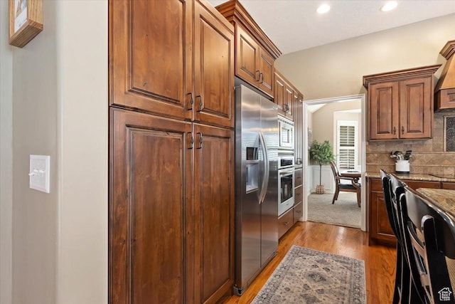 kitchen featuring tasteful backsplash, light wood-type flooring, recessed lighting, light stone counters, and stainless steel appliances