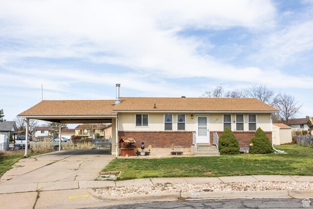 ranch-style home with an attached carport, a front yard, brick siding, and fence