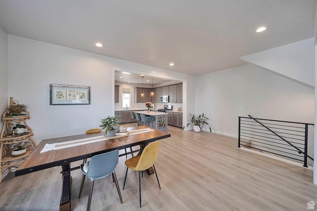 dining room with light wood-style flooring, recessed lighting, and baseboards