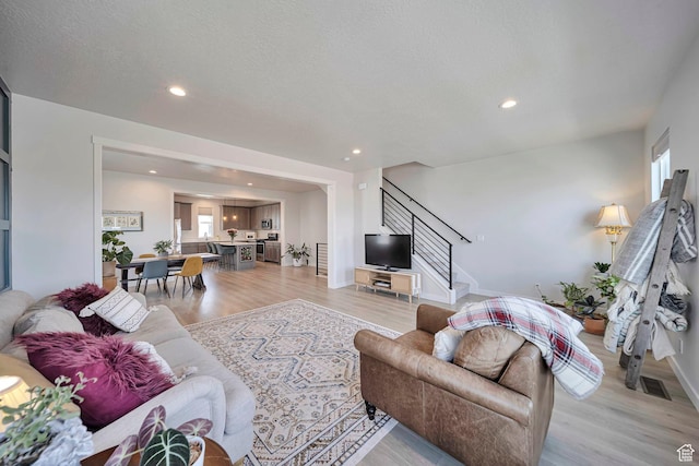 living area with visible vents, light wood-style flooring, recessed lighting, and stairs