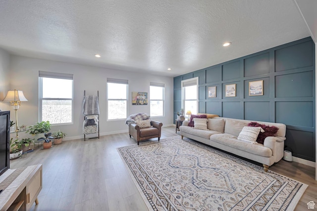 living area featuring recessed lighting, a decorative wall, light wood-style floors, and a textured ceiling