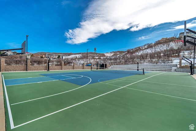 view of basketball court featuring community basketball court, fence, and a mountain view