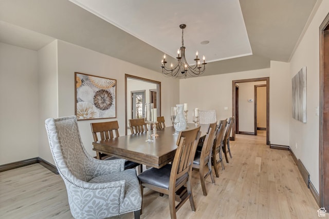 dining area featuring light wood-type flooring, an inviting chandelier, and baseboards