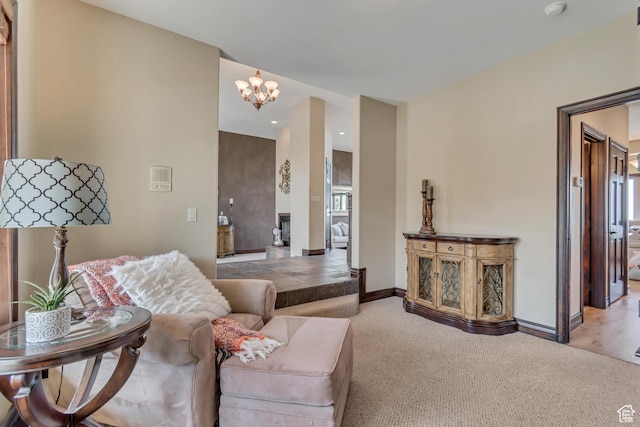 living area with baseboards, an inviting chandelier, and light colored carpet