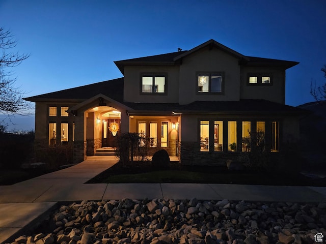 back of house with stone siding and stucco siding