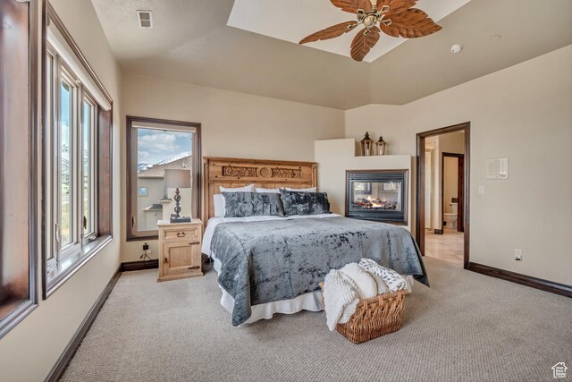 bedroom featuring visible vents, baseboards, a multi sided fireplace, a ceiling fan, and light carpet