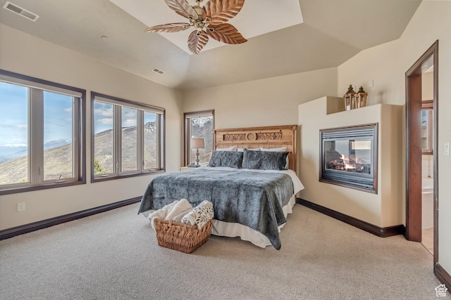 bedroom with visible vents, light colored carpet, a multi sided fireplace, and a ceiling fan