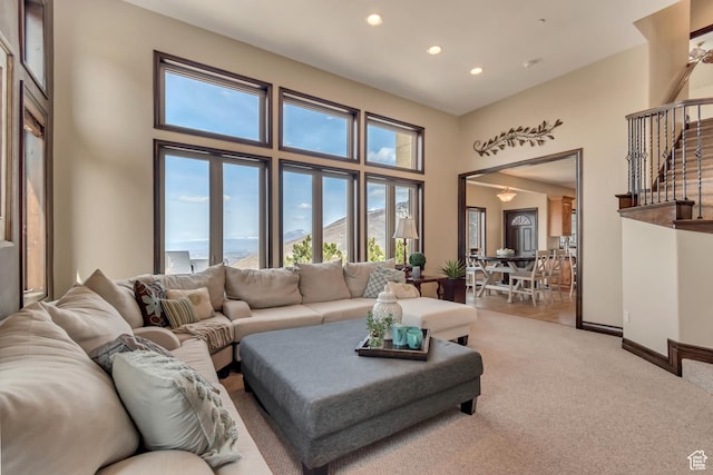 living room featuring baseboards, stairway, recessed lighting, a towering ceiling, and light colored carpet