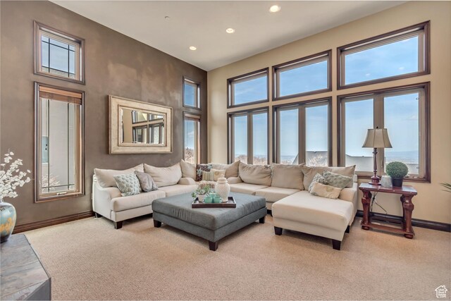 living room with a wealth of natural light, a towering ceiling, baseboards, and carpet floors