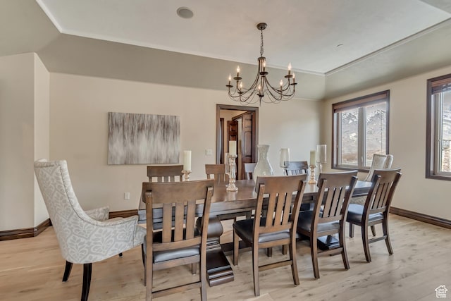 dining room with a chandelier, a tray ceiling, light wood-type flooring, and baseboards