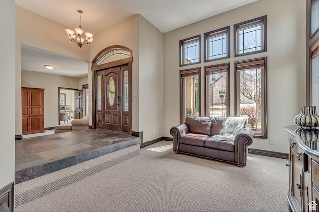 carpeted entryway with a notable chandelier, baseboards, and a towering ceiling