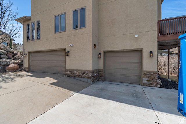 exterior space with stone siding, a garage, and stucco siding