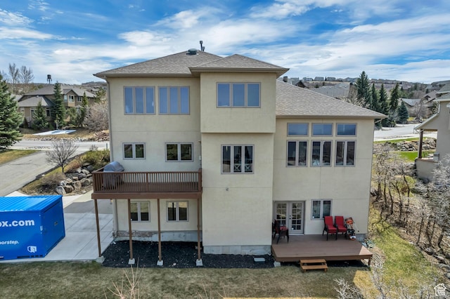 rear view of house featuring french doors, a shingled roof, a wooden deck, and stucco siding