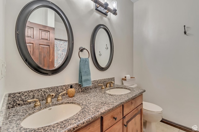 bathroom with double vanity, a sink, and toilet