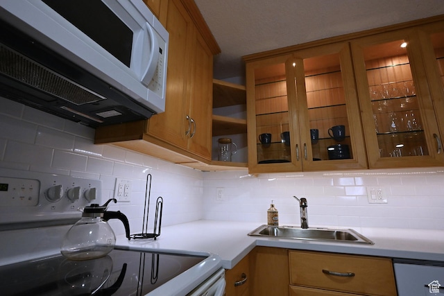 kitchen featuring a sink, light countertops, brown cabinetry, white microwave, and range