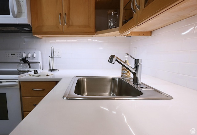 kitchen featuring white appliances, light countertops, a sink, and decorative backsplash