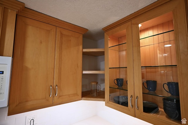 details with white microwave, a textured ceiling, and brown cabinetry