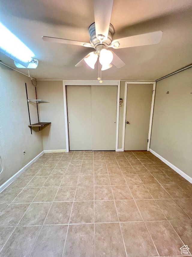 unfurnished bedroom with light tile patterned floors, ceiling fan, and baseboards