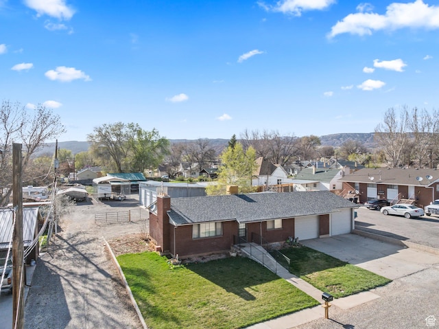 view of front of property with concrete driveway, a residential view, a chimney, a front yard, and brick siding