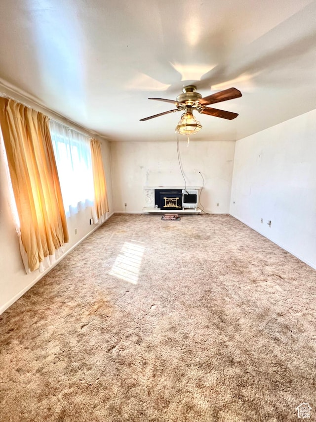 unfurnished living room featuring a ceiling fan and carpet flooring