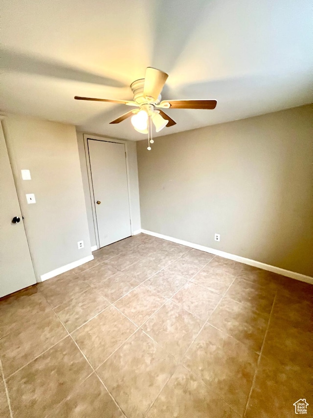 tiled empty room with baseboards and a ceiling fan