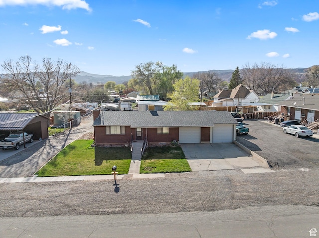 ranch-style house with a front yard, a mountain view, a garage, concrete driveway, and roof with shingles