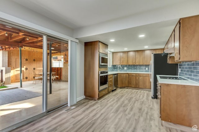 980 Hudson St, Ogden, UT 84404 - kitchen with light countertops, light wood-style floors, under cabinet range hood, brown cabinetry, and stainless steel appliances