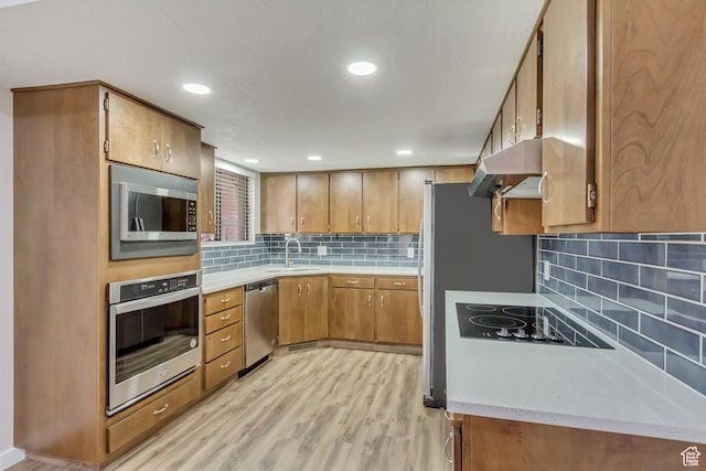 980 Hudson St, Ogden, UT 84404 - kitchen featuring a sink, light wood-type flooring, under cabinet range hood, brown cabinetry, and stainless steel appliances