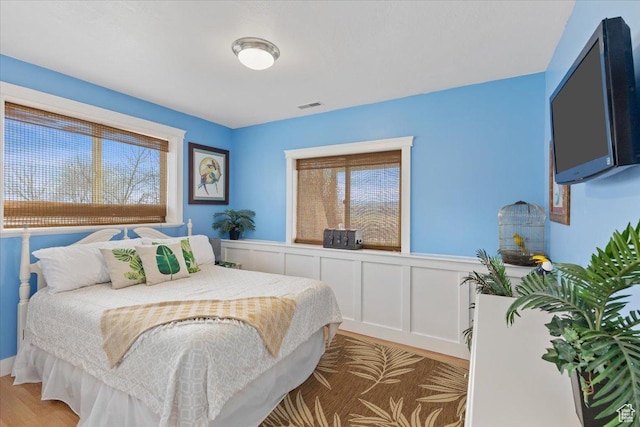 106 N Bear River Blfs, Preston, ID 83263 - bedroom featuring multiple windows, a wainscoted wall, light wood-style floors, and a decorative wall