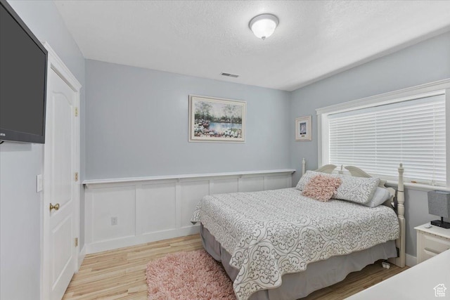106 N Bear River Blfs, Preston, ID 83263 - bedroom with light wood-type flooring, a textured ceiling, wainscoting, and a decorative wall