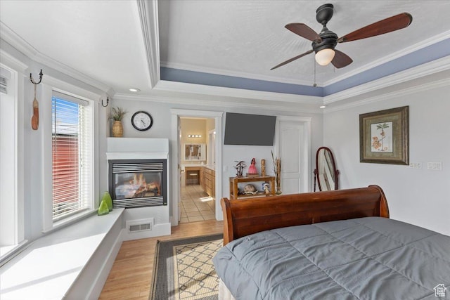 106 N Bear River Blfs, Preston, ID 83263 - bedroom featuring ornamental molding, a raised ceiling, light wood-type flooring, a glass covered fireplace, and ceiling fan