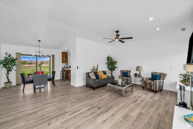 living room featuring visible vents, baseboards, light wood-style floors, and ceiling fan with notable chandelier