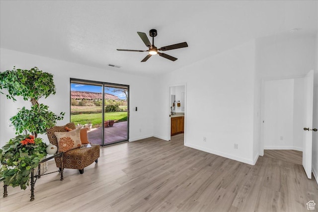 living area featuring light wood finished floors, visible vents, baseboards, and a ceiling fan