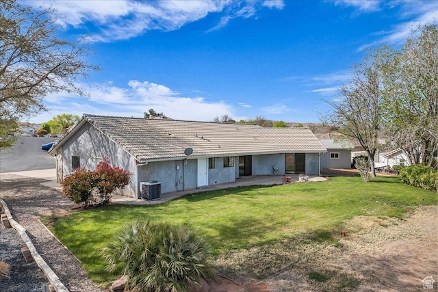 back of house with a tiled roof, cooling unit, stucco siding, a lawn, and a patio area