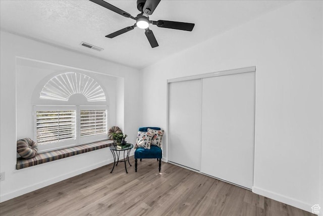 sitting room with visible vents, baseboards, a ceiling fan, and wood finished floors