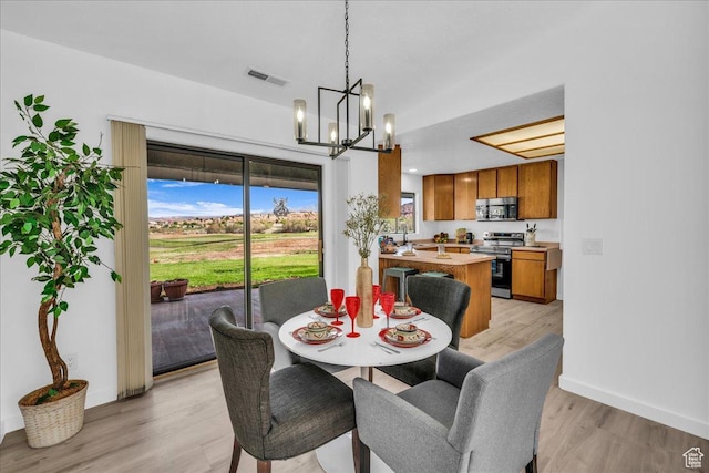dining room with visible vents, light wood-style flooring, a chandelier, and baseboards